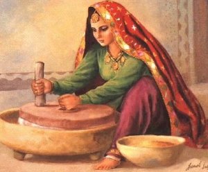 A traditionally dressed woman using a chakki or a stone mill